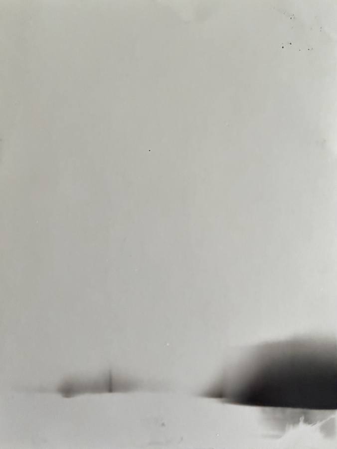 Pinhole photograph: a pale field with a dark rounded shape low on the right