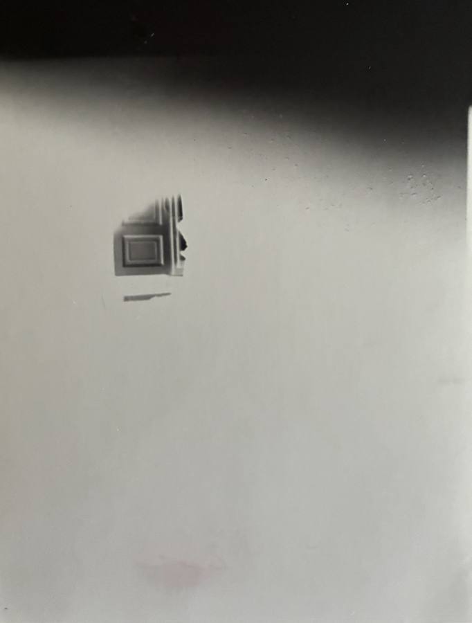 Pinhole photograph: a small doorway in a pale field beneath a dark band