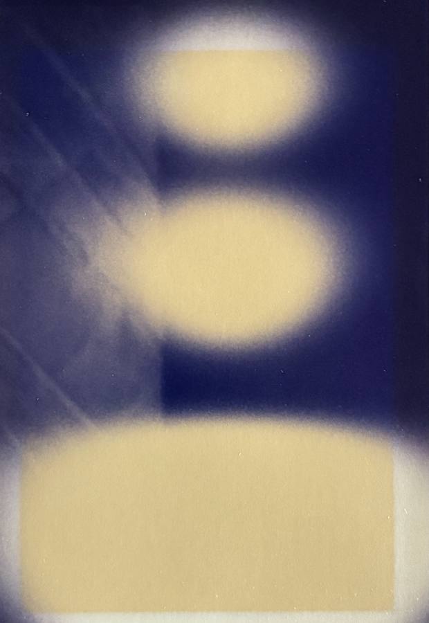 Pinhole photograph: two pale ovals stacked above a pale band on deep blue